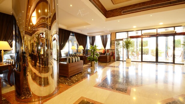A spacious lobby with a curved glass wall, a seating area with sofas, and a large potted plant. - Qasr Al Sahab (Khamis Mushait)