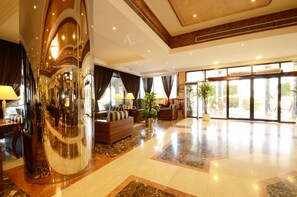 A spacious lobby with a curved glass wall, a seating area with sofas, and a large potted plant. - Qasr Al Sahab (Khamis Mushait)