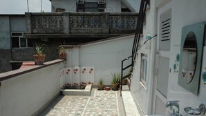 Un petit espace extérieur clos, doté d’un sol carrelé, d’un évier et de plantes en pot.