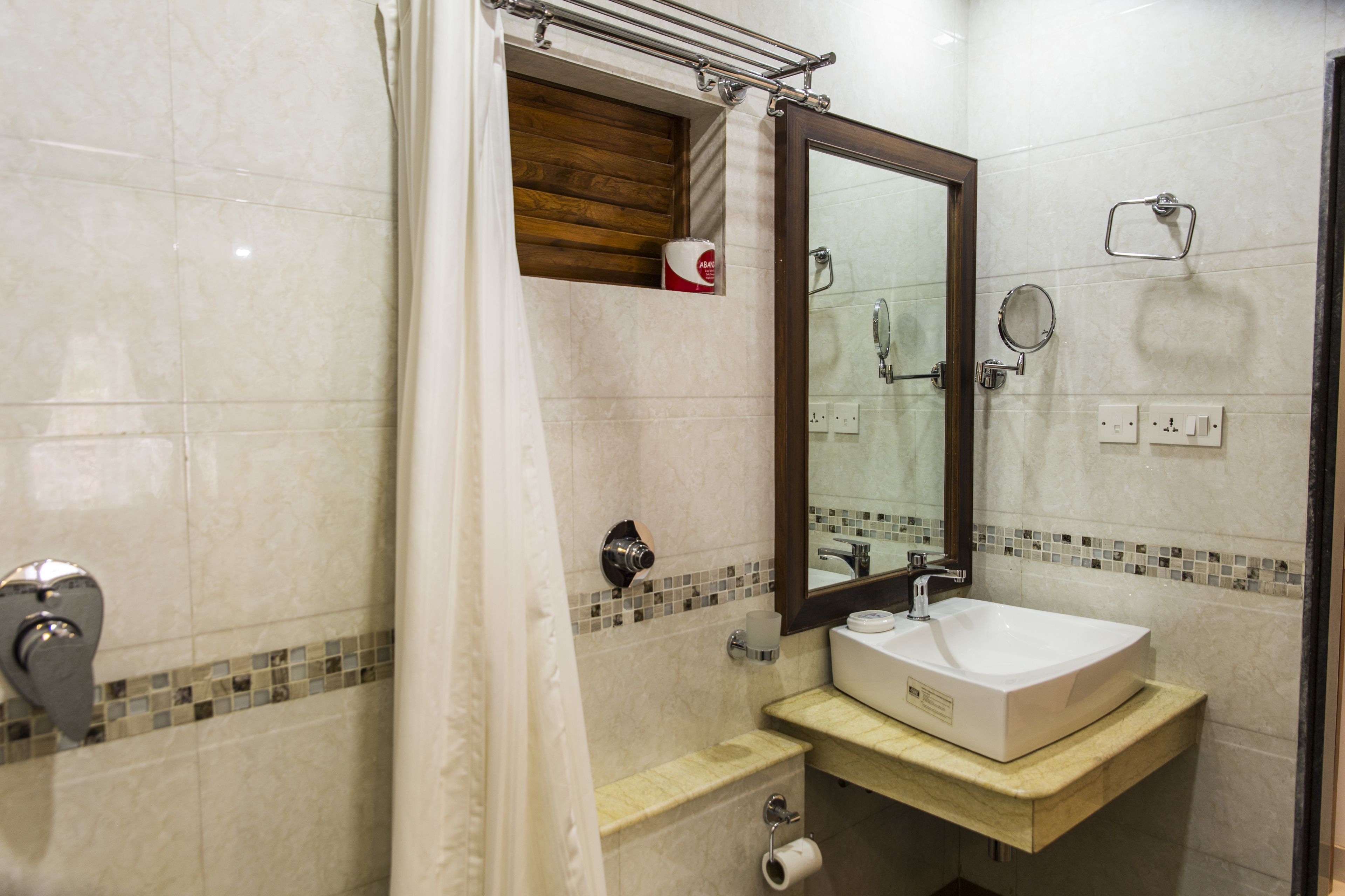 A bathroom with a white sink, a mirror, a shower curtain, and a toilet paper holder.