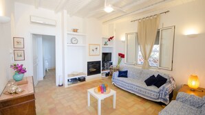 Una sala de estar con un sofá, una mesita baja con objetos de colores, una chimenea y un televisor.
