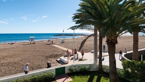 A beach with palm trees, a lifeguard tower, and people relaxing. - Beachfront Las Burras MRA 02 by VillaGranCanaria (San Bartolomé de Tirajana)