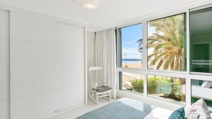 A bedroom with a large window, a bed, a rocking chair, and a view of the beach. - Beachfront Las Burras MRA 02 by VillaGranCanaria (San Bartolomé de Tirajana)