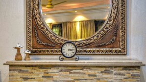 A fireplace with a stone facade, a decorative mirror above it, and a clock below the mirror. - Lahore Home Stay (Lahore)