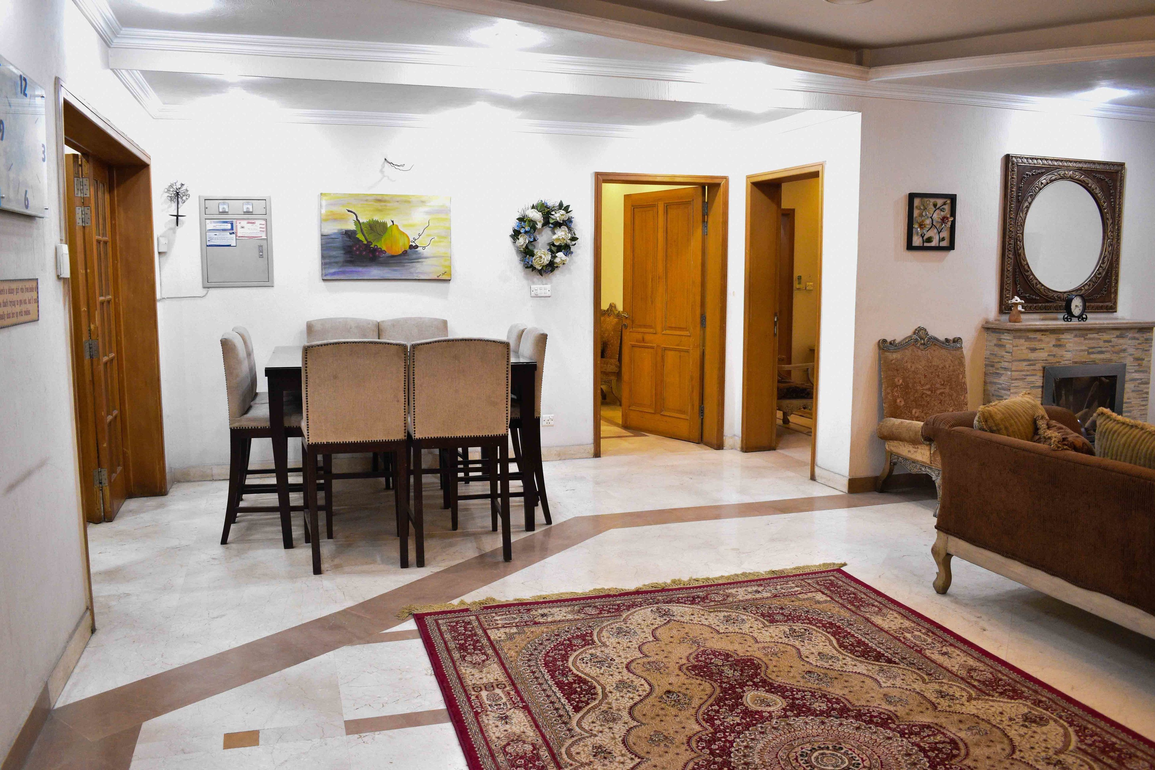 A living room with a fireplace, a dining area with a table and chairs, and a hallway leading to another room.