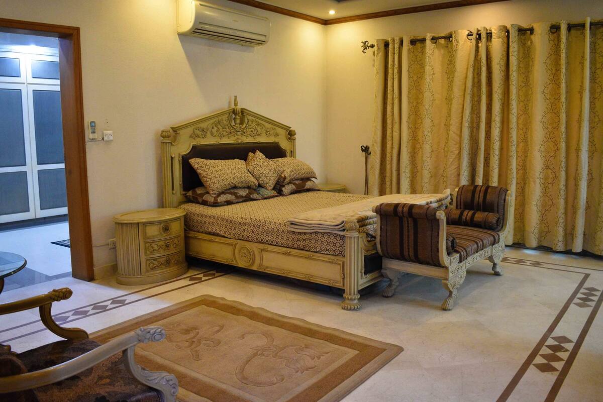 A bedroom with a bed, nightstand, chair, and a window with curtains.