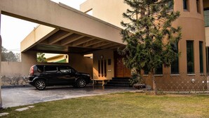 A black SUV parked under a covered area with a building in the background. - Lahore Home Stay (Lahore)