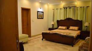 A bedroom with a wooden bed, a nightstand, a chair, and a door. - Lahore Home Stay (Lahore)