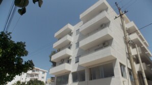 Un immeuble à plusieurs étages, doté de balcons, de grandes fenêtres et surplombant un ciel dégagé.