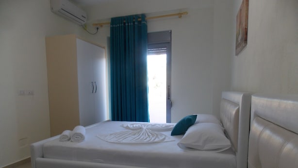 Une chambre d’hôtel avec deux lits, une salle de bain et une fenêtre avec des rideaux.