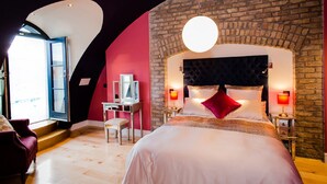 Een moderne slaapkamer met een groot bed, een stenen muur en een gebogen plafond.