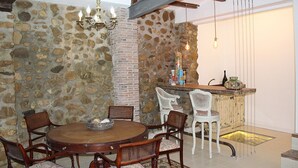 Un comedor con pared de piedra, mesa de madera y sillas.