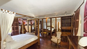 Un dormitorio con cama con dosel, un escritorio de madera, una silla y un armario.