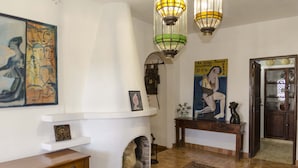 Un vestíbulo con chimenea, un banco de madera, una alfombra y obras de arte en las paredes.