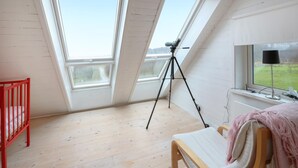 A room with a sloped ceiling, a telescope on a tripod, a television on a stand, a red crib, and a bench with a pink blanket. - Awesome home in östra sönnarslöv (Östra Sönnarslöv)