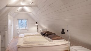 A small, narrow attic bedroom with a sloped ceiling, a window providing natural light, a bedside table with a lamp, and a bed with pillows. - Awesome home in östra sönnarslöv (Östra Sönnarslöv)