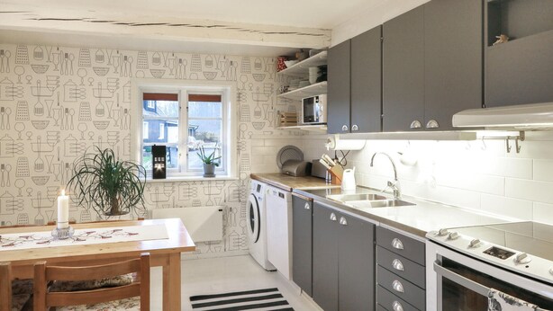 A compact kitchen with grey cabinets, a built-in microwave, and a washing machine. - Awesome home in östra sönnarslöv (Östra Sönnarslöv)