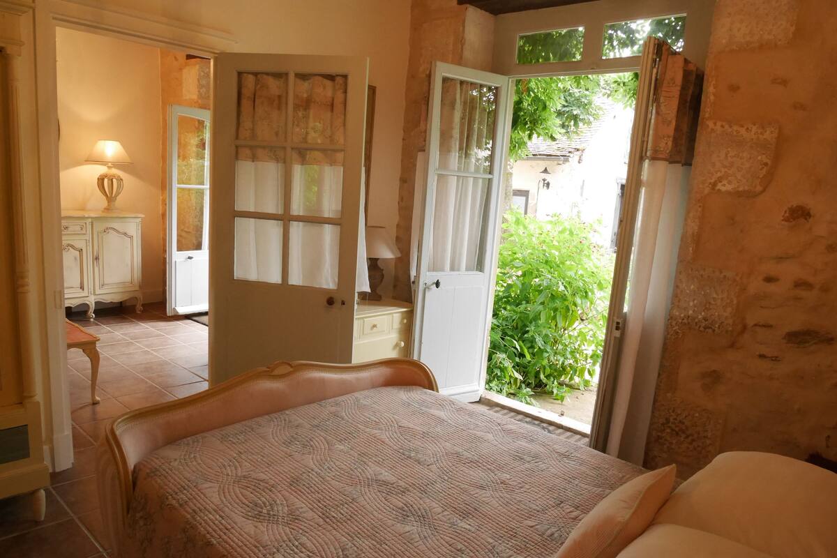 A bedroom with a bed, a dresser, and a door leading to a balcony.