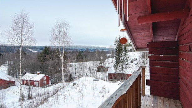 A wooden cabin with a balcony overlooking a snowy landscape with houses and trees. - Beautiful home in Ambjörby with sauna (Ambjörby)