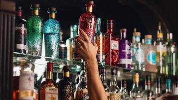 Una mano eligiendo una botella de un estante lleno de diferentes licores.