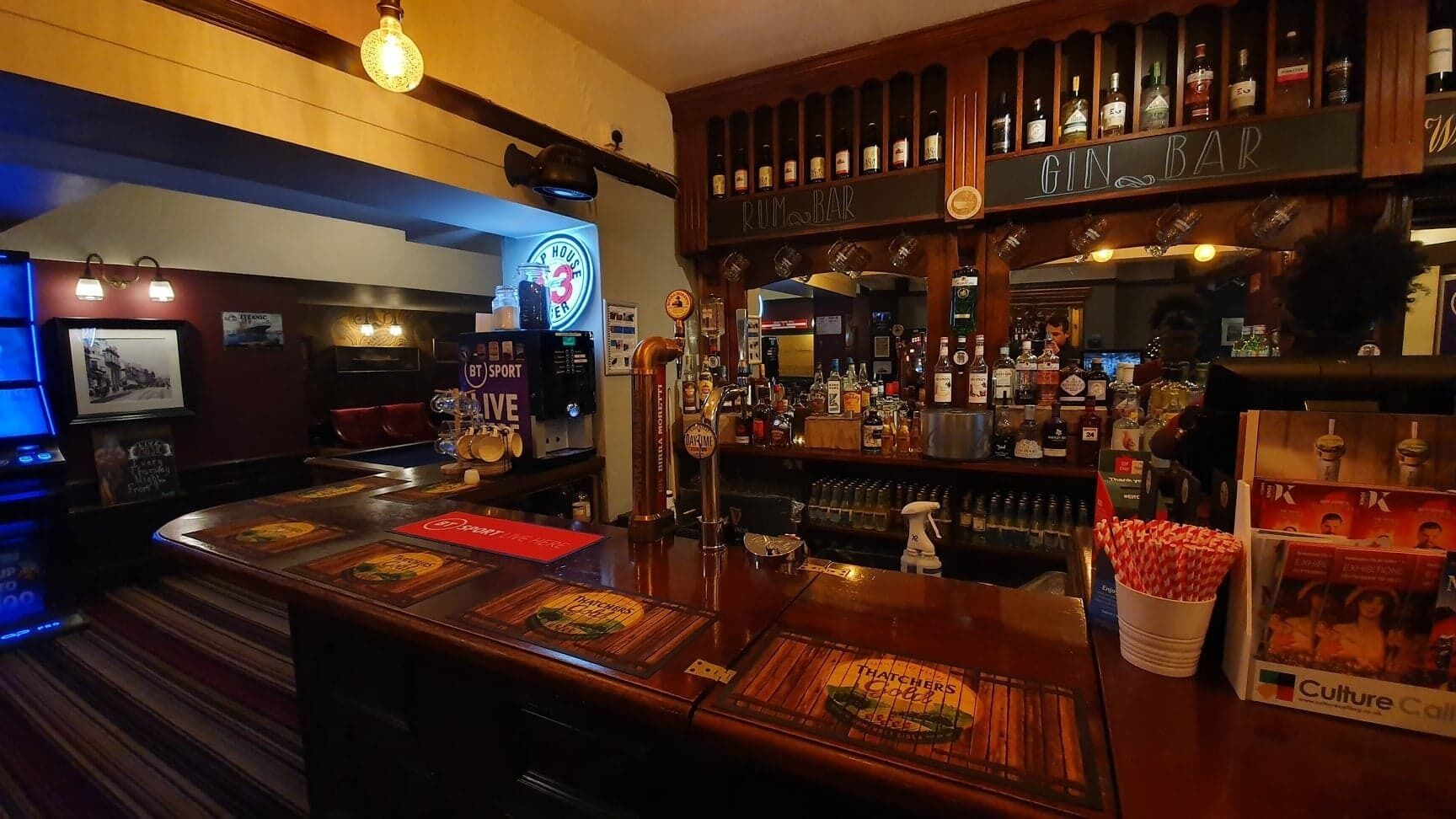 A bar area with a counter, various bottles, and a sign for 'Rum Bar'.