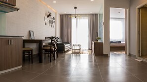 Une cuisine moderne avec un coin repas, un canapé et une vue sur une chambre à coucher, visible à travers une porte.