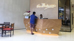 Un comptoir d’accueil avec une enseigne indiquant « The Botanica », et une femme assise derrière.