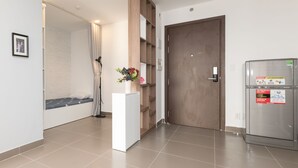 Une chambre d’hôtel équipée d’un lit, d’une armoire, d’un réfrigérateur et d’un petit bureau agrémenté d’une plante.