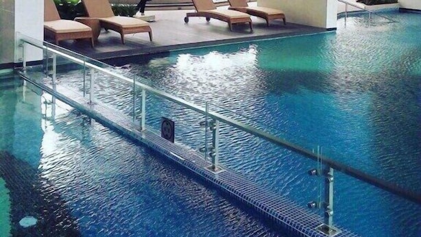 Une piscine intérieure dotée de chaises longues et offrant une vue sur les bâtiments environnants.