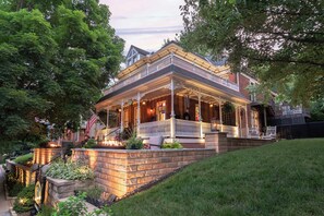 A large, two-story house with a porch, brick steps, and a well-maintained lawn. - Main Street Inn (Parkville)