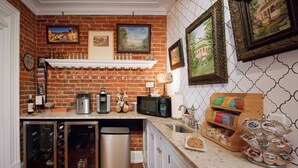 A kitchen with a brick wall, a microwave, a coffee maker, and a sink. - Main Street Inn (Parkville)