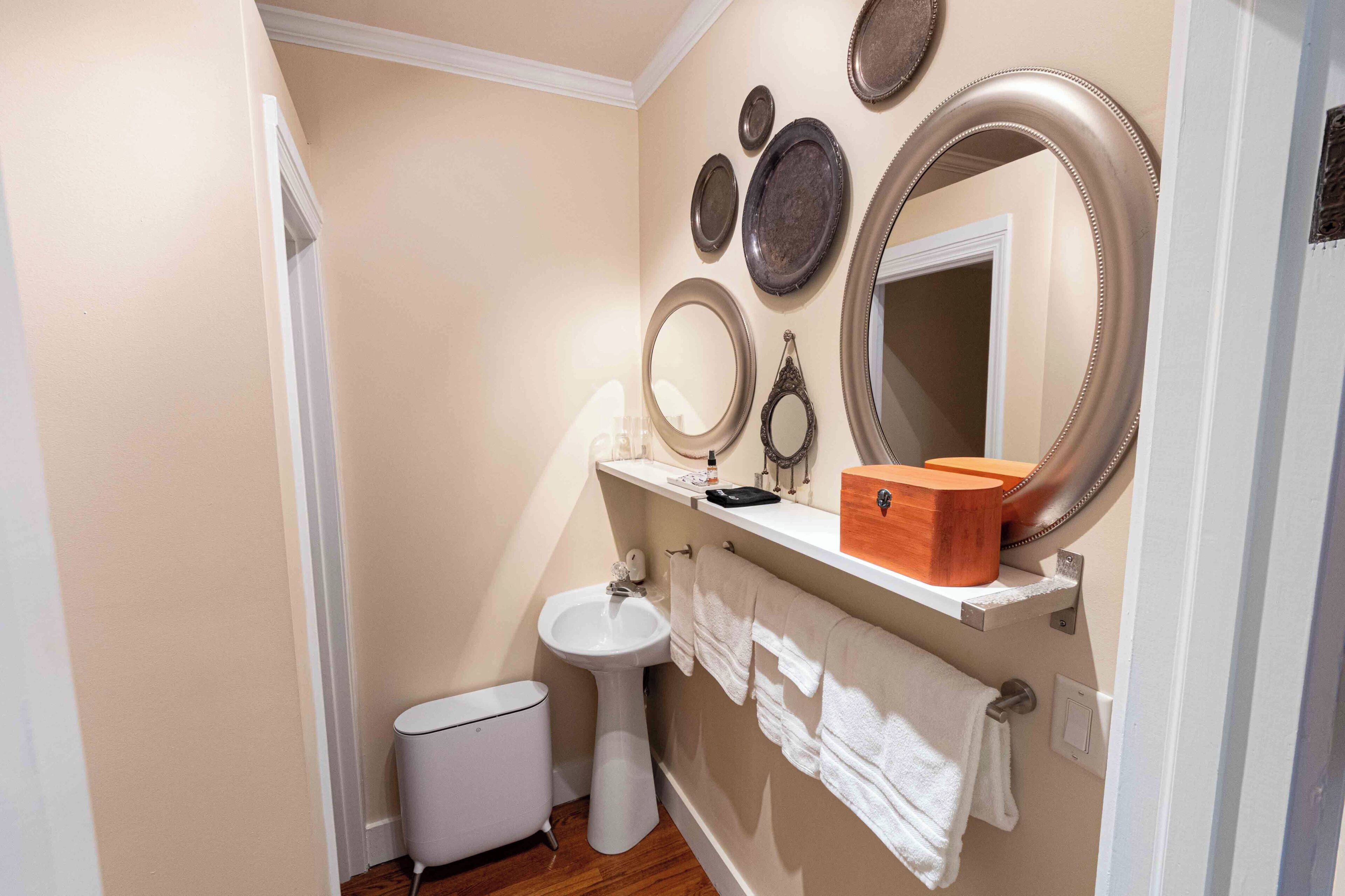 A bathroom with a pedestal sink, a toilet, a bidet, and a mirror with decorative plates.