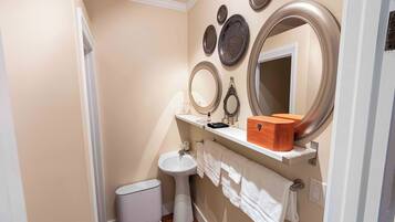 A bathroom with a pedestal sink, a toilet, a bidet, and a mirror with decorative plates.
