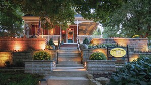 A brick building with a porch, steps leading to a door, and a sign indicating 'Main Street Inn.' - Main Street Inn (Parkville)
