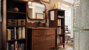 A wooden dresser with drawers, a mirror, and a bookshelf filled with books. - Main Street Inn (Parkville)