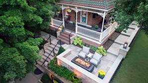 A covered patio with outdoor seating, a fire pit, and a brick building with a porch. - Main Street Inn (Parkville)