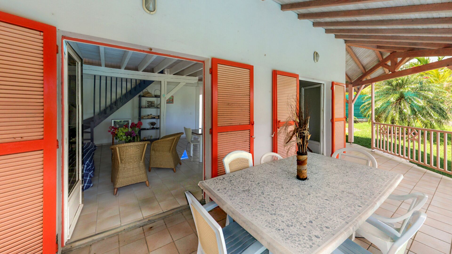 An open patio with a dining table, chairs, and a staircase leading to an upper level.