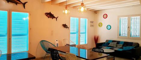 A dining area with a table and chairs, a sofa, and decorative fish on the wall.
