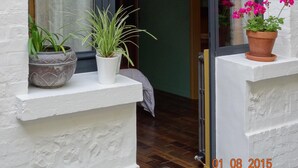 Een raam met uitzicht op een gang en een deur. Op de vensterbank staan potplanten.