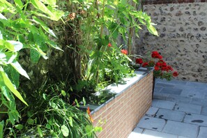 A brick planter box with various plants and red flowers. - In the heart of FECAMP Sea and Port JACUZZI pleasant terrace WIFI NORMANDY (Fécamp)