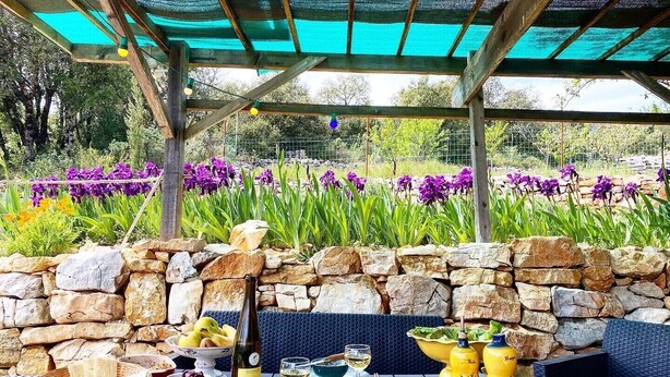 Un espace de restauration en plein air avec des murs en pierre, des meubles en osier et une variété de plats et de boissons.