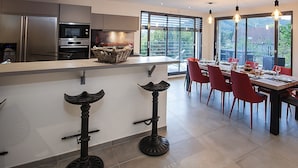 A modern kitchen with a large island, red bar stools, and a dining area with a table set for six.