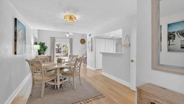 A spacious dining area with a wooden table and chairs, a ceiling fan, and a hanging light fixture. -  Island Breeze in Vilano Beach Peaceful Getaway (Jacksonville)