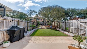 A backyard with a wooden fence, a barbecue grill, a lawn, and a patio area. -  Island Breeze in Vilano Beach Peaceful Getaway (Jacksonville)