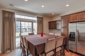 A dining area with a table, chairs, and a refrigerator.