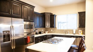 A modern kitchen with dark cabinets, stainless steel appliances, and a central island with seating. - SPOTLESS,Booking for SUMMER FALL AND WINTER 3bdrm 2bth ONE LEVEL Great location! (Washington)