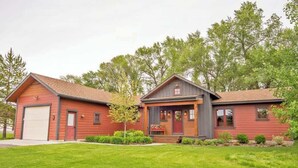 Een huis met twee verdiepingen, een garage, een voortuin en een verzorgd gazon.