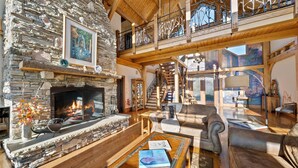 Ein geräumiger Wohnbereich mit Kamin aus Stein, Holzbalken und einem Balkon mit schmiedeeisernen Geländern.