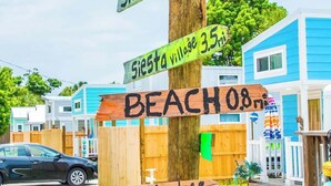 Een houten bord met aanduidingen naar verschillende locaties, waaronder Tiny House Siesta, Siesta Key Beach, Siesta Village en Lido Beach.