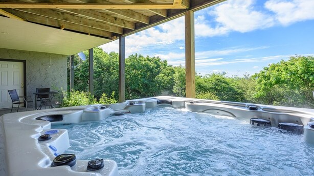 Un espace avec plusieurs bains à remous, installé sous une pergola en bois et entouré de verdure.
